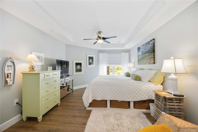 bedroom featuring ceiling fan, a tray ceiling, and dark hardwood / wood-style flooring