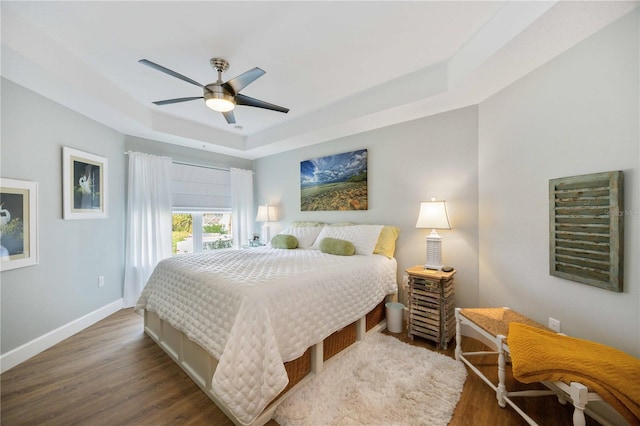 bedroom featuring a raised ceiling, dark hardwood / wood-style floors, access to exterior, and ceiling fan