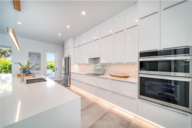 kitchen with sink, decorative backsplash, appliances with stainless steel finishes, and white cabinets