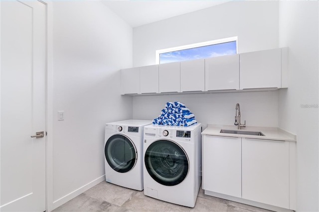 clothes washing area featuring sink, washing machine and clothes dryer, and cabinets