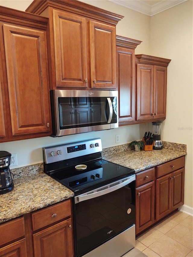 kitchen with light stone countertops, ornamental molding, appliances with stainless steel finishes, and light tile patterned flooring