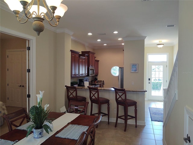 dining space with crown molding, a notable chandelier, and light tile patterned floors