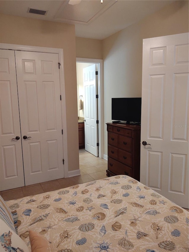 bedroom featuring a closet, ceiling fan, connected bathroom, and light tile patterned floors