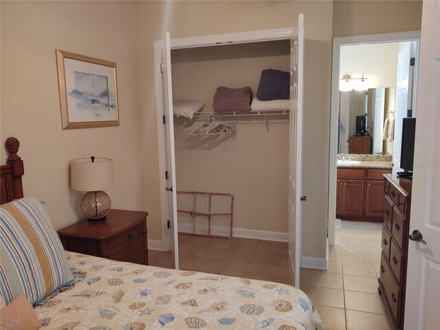 bedroom with sink, ensuite bathroom, a closet, and light tile patterned floors