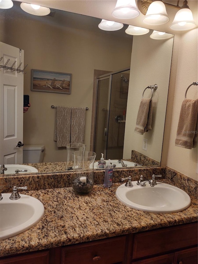 bathroom with vanity, a shower with shower door, and toilet