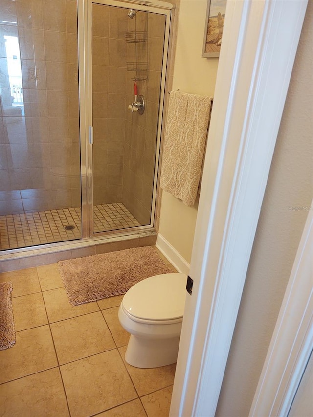 bathroom with a shower with shower door, toilet, and tile patterned flooring