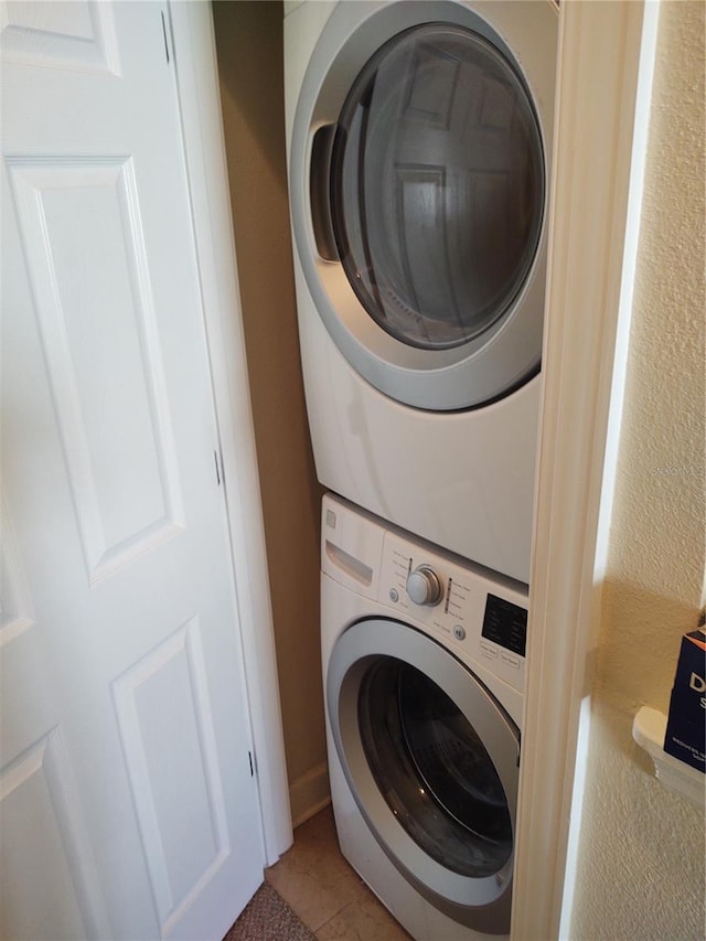 clothes washing area featuring stacked washer / drying machine and light tile patterned floors