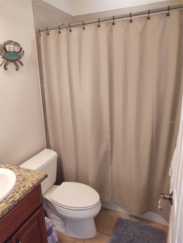 bathroom featuring walk in shower, vanity, toilet, and tile patterned flooring