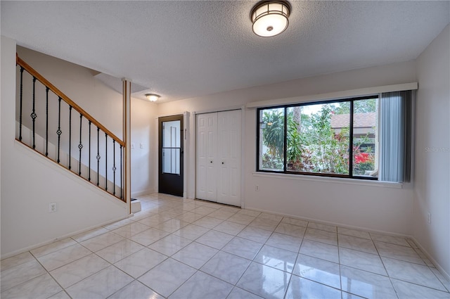 entrance foyer featuring a textured ceiling and light tile patterned floors