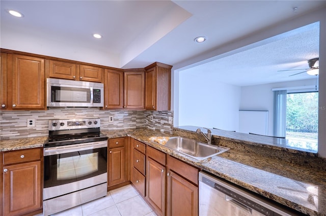 kitchen featuring decorative backsplash, sink, stainless steel appliances, and dark stone counters