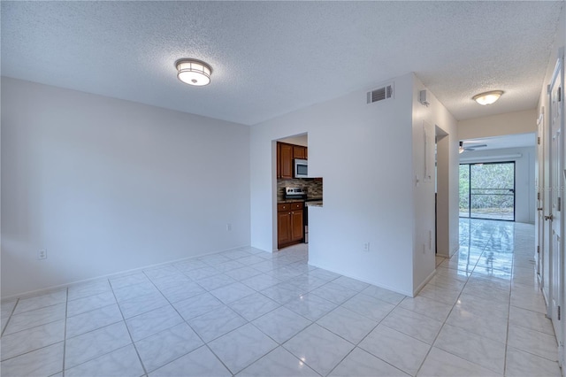 tiled spare room with ceiling fan and a textured ceiling