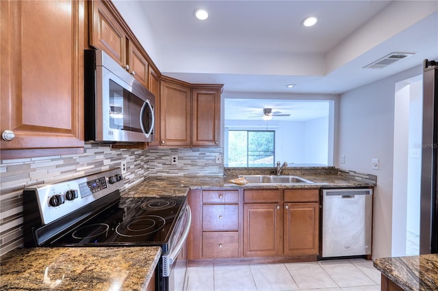 kitchen with sink, dark stone countertops, stainless steel appliances, and tasteful backsplash