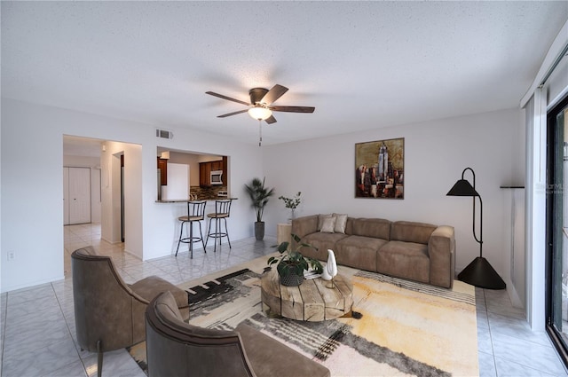 tiled living room with a textured ceiling and ceiling fan