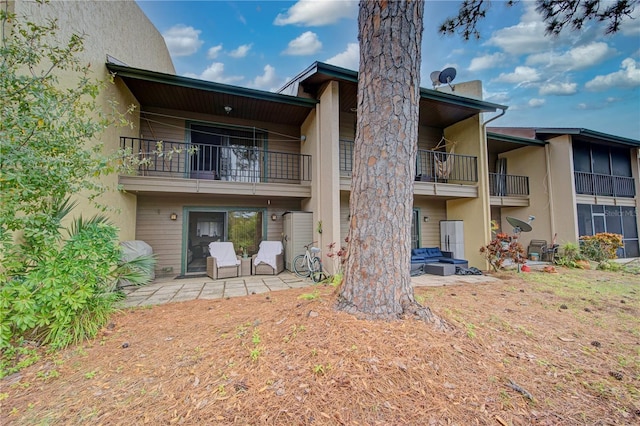 rear view of property featuring a balcony, outdoor lounge area, and a patio