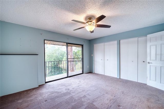 unfurnished bedroom featuring ceiling fan, carpet floors, access to exterior, two closets, and a textured ceiling