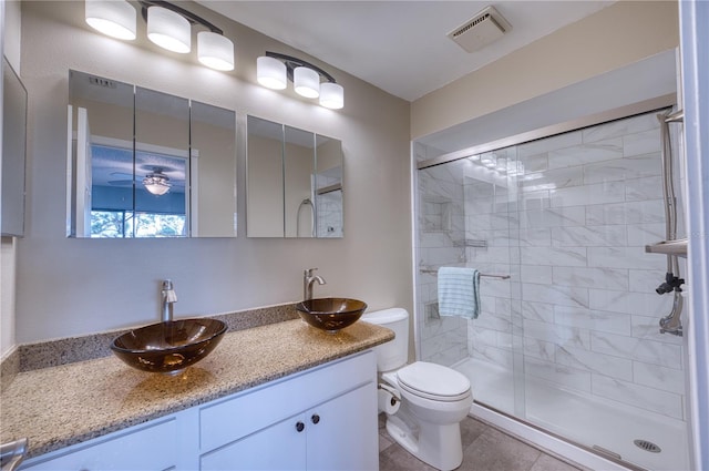 bathroom featuring toilet, ceiling fan, tile patterned floors, an enclosed shower, and vanity