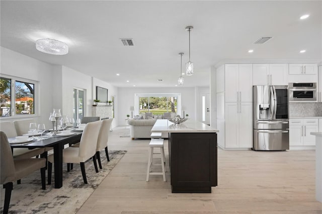 kitchen featuring light wood-type flooring, pendant lighting, appliances with stainless steel finishes, and white cabinets