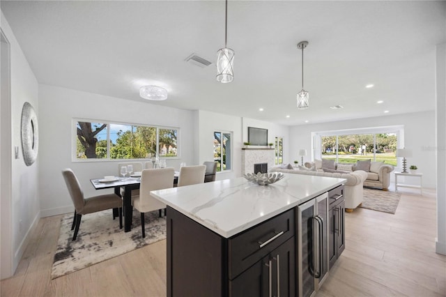 kitchen featuring hanging light fixtures, light hardwood / wood-style floors, beverage cooler, and a center island