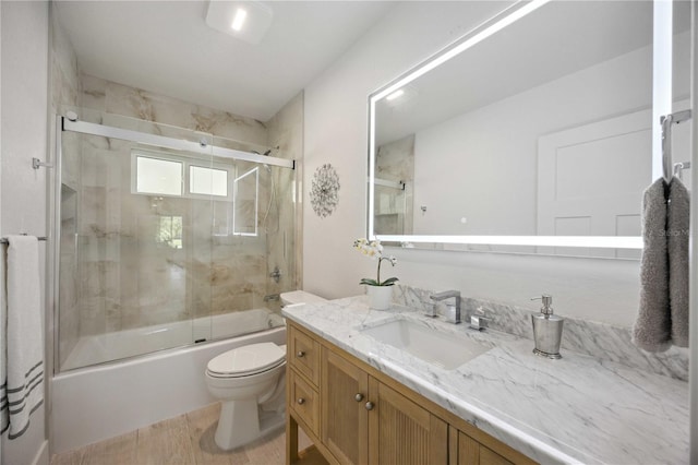 full bathroom with combined bath / shower with glass door, vanity, and toilet