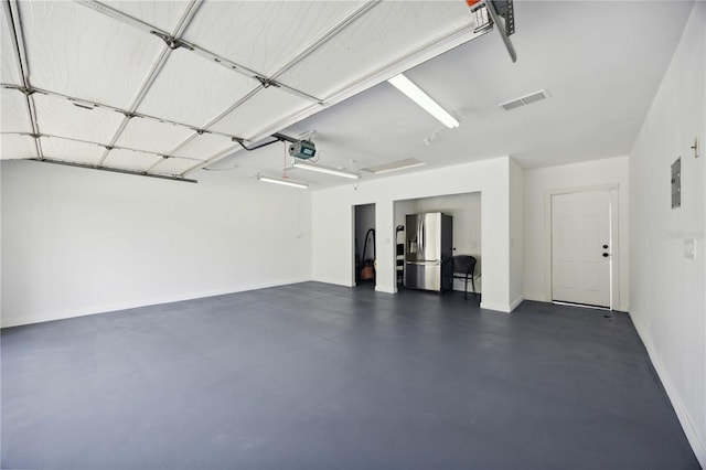 garage with stainless steel refrigerator with ice dispenser and a garage door opener