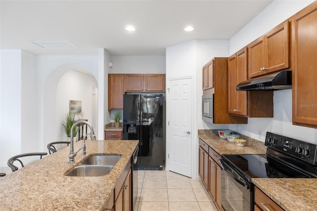 kitchen featuring black appliances, sink, light stone counters, and light tile patterned floors