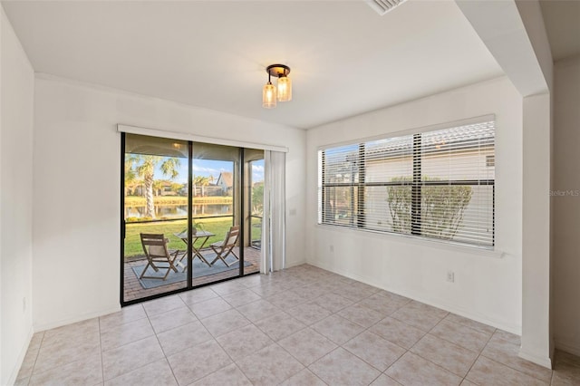 empty room featuring a water view and light tile patterned floors