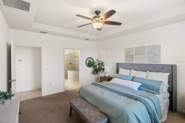 carpeted bedroom featuring ensuite bath, ceiling fan, and a tray ceiling