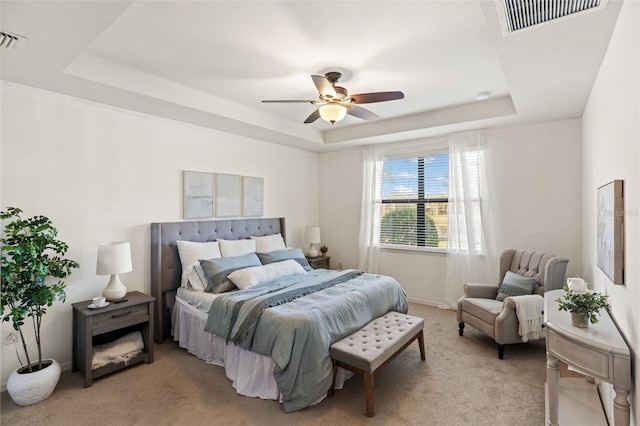 carpeted bedroom featuring ceiling fan and a tray ceiling