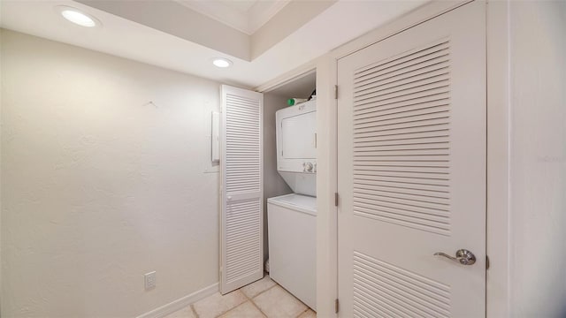 clothes washing area with light tile patterned flooring and stacked washer and dryer