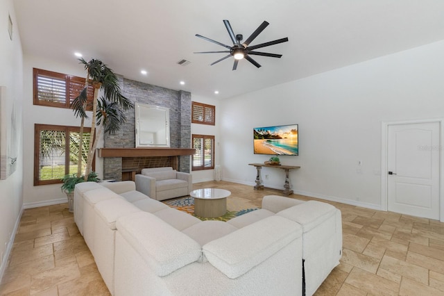 living room featuring a fireplace, a high ceiling, and ceiling fan