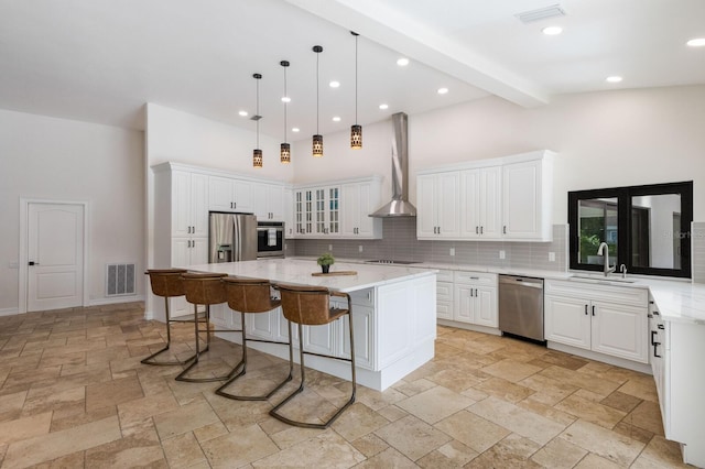 kitchen featuring a kitchen island, white cabinetry, appliances with stainless steel finishes, sink, and wall chimney exhaust hood