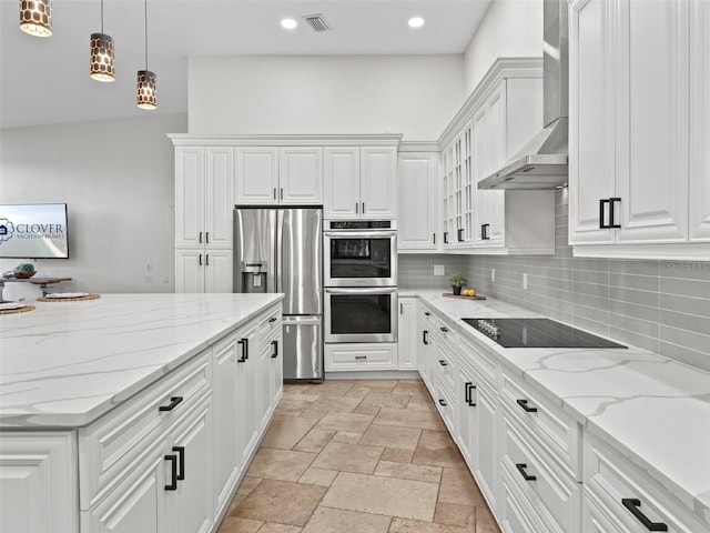 kitchen with wall chimney range hood, appliances with stainless steel finishes, decorative light fixtures, light stone countertops, and white cabinets