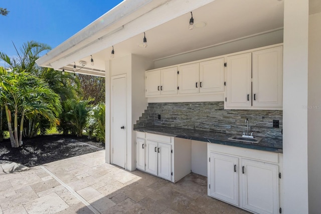 kitchen with tasteful backsplash, sink, and white cabinets