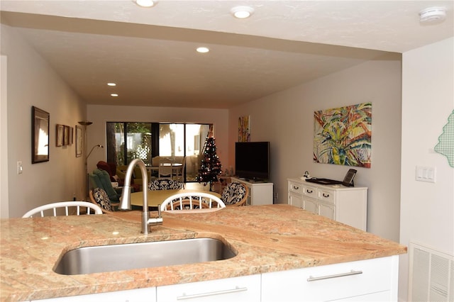 kitchen featuring white cabinetry, sink, and light stone counters