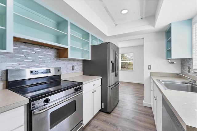 2420 Sunnyside St, Sarasota, FL 34239 - kitchen with appliances with stainless steel finishes, open shelves, a tray ceiling, wood finished floors, and decorative backsplash