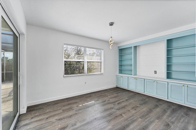 unfurnished dining area with dark wood-type flooring and built in features