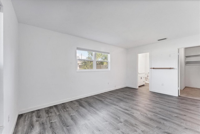 unfurnished bedroom featuring connected bathroom, a closet, and wood-type flooring