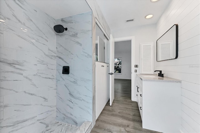 bathroom with vanity, hardwood / wood-style flooring, and tiled shower