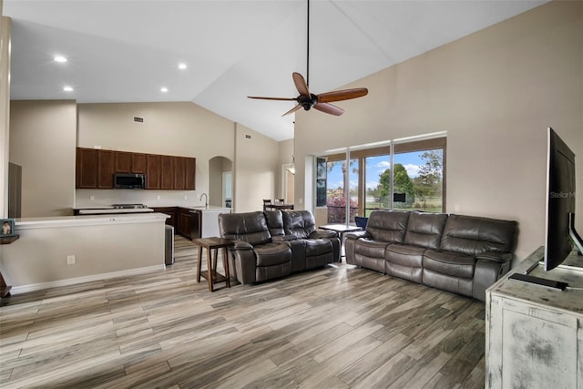 living room with light hardwood / wood-style flooring, high vaulted ceiling, sink, and ceiling fan