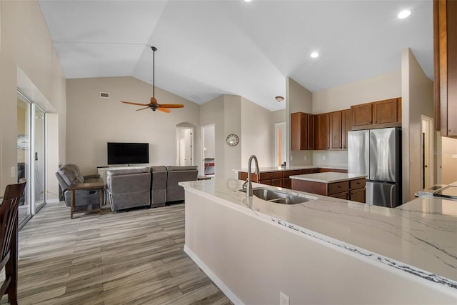 kitchen featuring sink, kitchen peninsula, stainless steel fridge, ceiling fan, and light hardwood / wood-style flooring