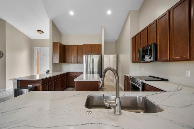 kitchen with kitchen peninsula, hardwood / wood-style floors, light stone counters, appliances with stainless steel finishes, and sink