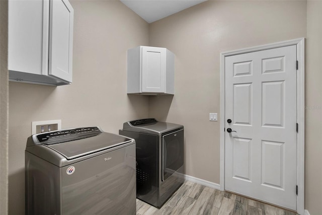 laundry room featuring light hardwood / wood-style floors, cabinets, and washer and clothes dryer