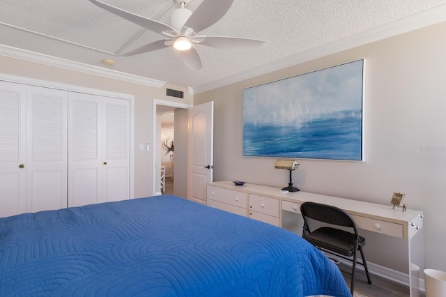 bedroom with built in desk, ceiling fan, a textured ceiling, wood-type flooring, and ornamental molding