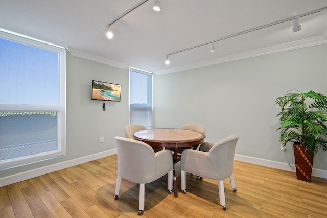 dining area featuring rail lighting, crown molding, and light hardwood / wood-style flooring