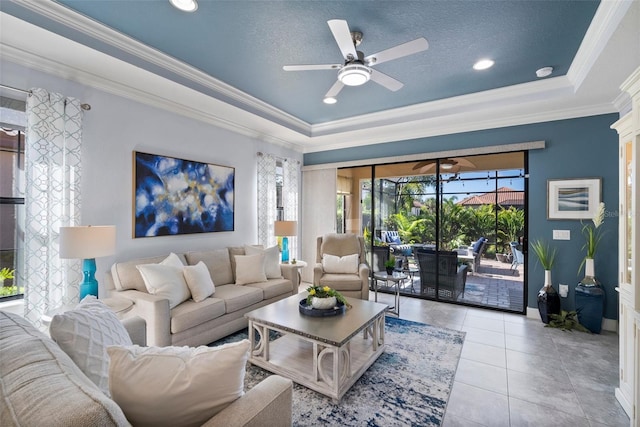 living room with ornamental molding, light tile patterned flooring, a raised ceiling, a textured ceiling, and ceiling fan