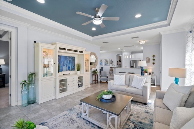 living room featuring crown molding, a tray ceiling, and ceiling fan