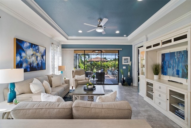 living room with crown molding, a raised ceiling, light tile patterned flooring, and ceiling fan