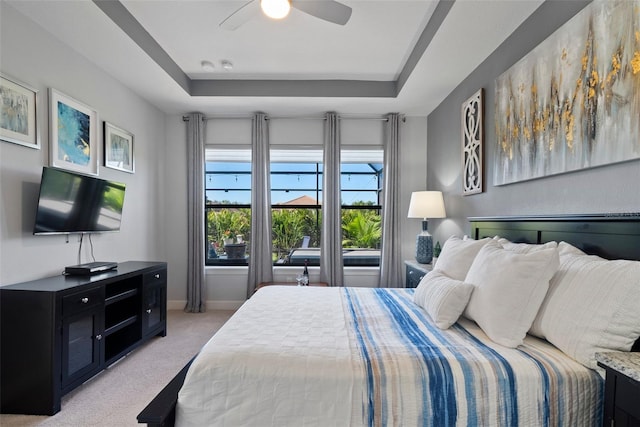 carpeted bedroom with a tray ceiling and ceiling fan