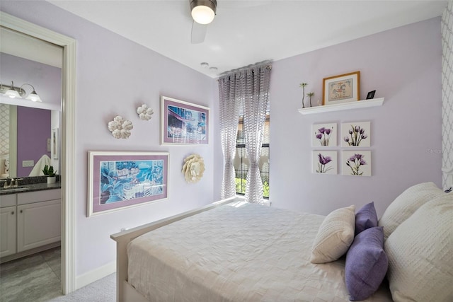 bedroom with ensuite bath, sink, light colored carpet, and ceiling fan