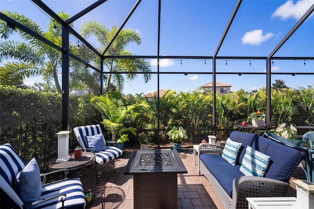 view of patio with a lanai and an outdoor living space with a fire pit